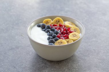 Kahvaltı smoothie kase. Taze kivi, yaban mersini, nar, granola, muz ve yoğurt ile Smoothie kase. Gri arka plan.  