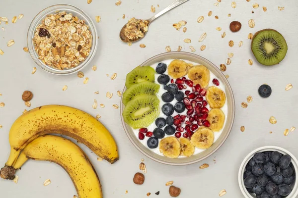 Breakfast smoothie bowl. Smoothie bowl with fresh kiwi, blueberry, pomegranate, granola, banana and yogurt. Grey background.