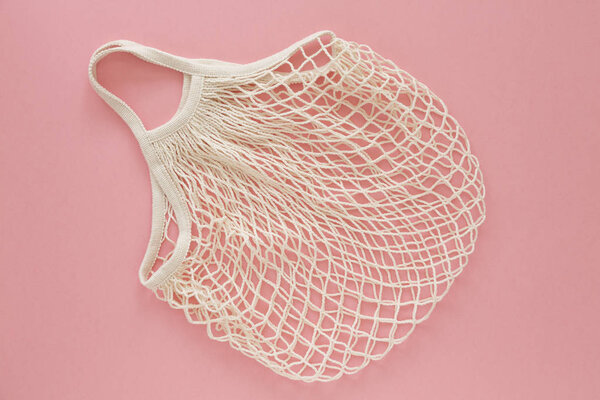 Eco friendly mesh bag on pink background. Concept caring for the environment and the rejection of plastic. Reusable net bag or mesh shopper. Flat lay. Top view. 