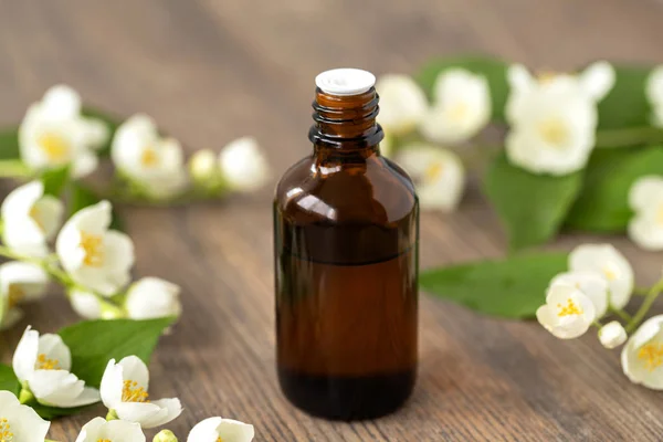 Essential aroma oil with jasmine on wooden background. Massage oil with jasmine flowers. Selective focus.
