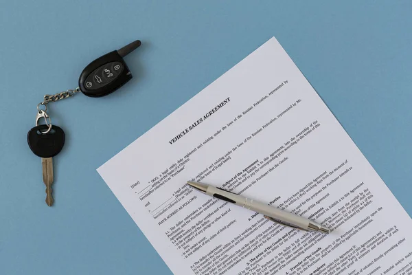 Rental agreement for a car with contract, pen and keys. Concept of selling, renting and insuring a car. Flat lay composition.