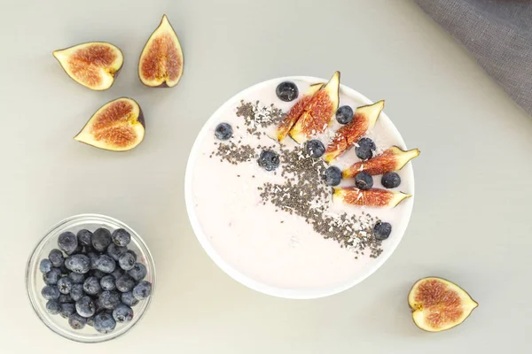 Healthy breakfast berry smoothie bowl topped with figs, coconut and chia seeds. Top view of a smoothie bowl with fresh ripe blueberry, figs, yogurt, coconut and chia. The concept of healthy eating and lifestyle.