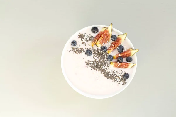 Healthy breakfast berry smoothie bowl topped with figs, coconut and chia seeds. Top view of a smoothie bowl with fresh ripe blueberry, figs, yogurt, coconut and chia. The concept of healthy eating and lifestyle.