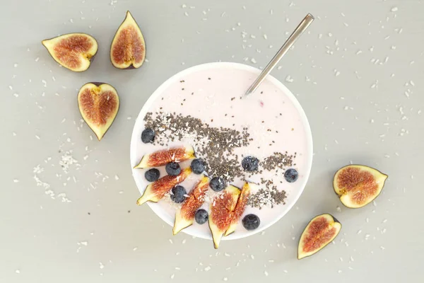 Healthy breakfast berry smoothie bowl topped with figs, coconut and chia seeds. Top view of a smoothie bowl with fresh ripe blueberry, figs, yogurt, coconut and chia. The concept of healthy eating and lifestyle.