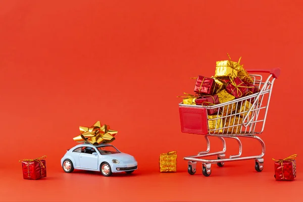 新年とクリスマスを祝うというコンセプト 屋根の上に大きな弓を持つ贈り物と小さな車でいっぱいのショッピングカート テキストのスペース — ストック写真