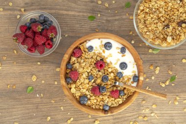 Ahşap arka plan üzerinde granola ve çilek taze ahududu ve yaban mersini ile Yoğurt. Üst te. Lezzetli ve sağlıklı Kahvaltı smoothie. Vejetaryen yemekler.