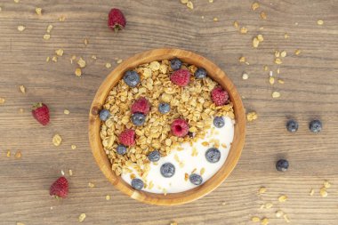 Ahşap arka plan üzerinde granola ve çilek taze ahududu ve yaban mersini ile Yoğurt. Üst te. Lezzetli ve sağlıklı Kahvaltı smoothie. Vejetaryen yemekler.