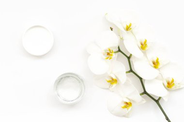 Beyaz arka plan üzerinde nemlendirici yüz jeli ve güzel orkide çiçekleri. Güzellik Spa konsepti. Jel ve Beyaz Phalaenopsis orkide ile açılan plastik konteyner. Organik Doğal kozmetik.