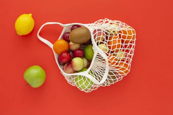 Mesh bag with fresh organic fruits on a colored background. Zero waste concept, Eco friendly or plastic free lifestyle. Top view