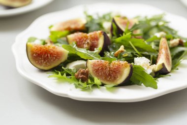 Roka salatası, incir, peynir, ceviz ve bal. Beyaz tabakta incir ve peynirli sonbahar salatası..