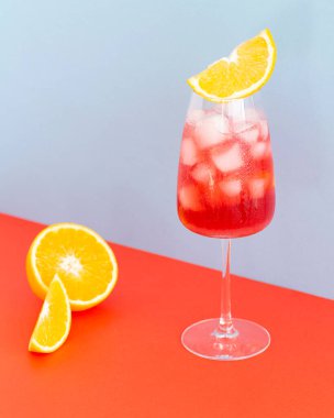 Renkli arkaplanda Aperol kokteyli. Buz küplü soğuk içecek. Bir bardak portakallı aperol spreyi. Yaz İtalyan kokteyli. Seçici odak