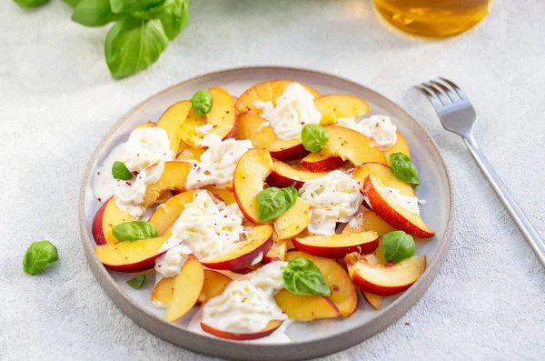Şeftalili taze salata, İtalyan Stracciatella peyniri, fesleğen, zeytinyağı ve bal. Yaz salatası, sağlıklı gıda konsepti. Seçici odak
