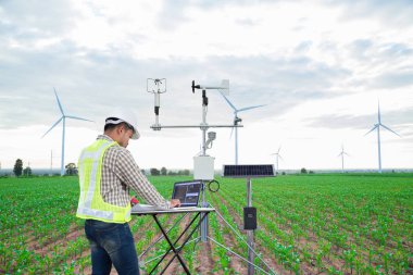 Engineer using tablet computer collect data with meteorological instrument to measure the wind speed, temperature and humidity and solar cell system on corn field background, Smart agriculture technology concept clipart