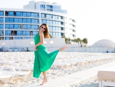 Yeşil bir elbisesi sahilde güzel genç kadın