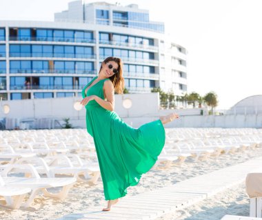 Yeşil bir elbisesi sahilde güzel genç kadın