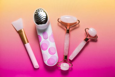 Parlak pembe ombre arka planda çeşitli yüz masajcıları