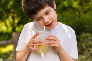 Sıcak bir yaz gününde limonata içen bir çocuk.
