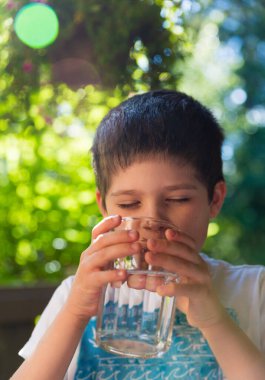 Sıcak bir yaz gününde su içen bir çocuk.