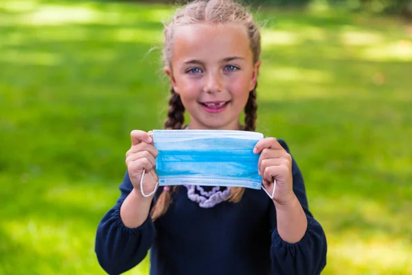 Feliz Colegiala Sonriente Mostrando Una Mascarilla Quirúrgica — Foto de Stock