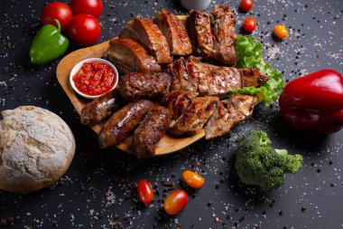 sosis ve domuz fırında pişmiş, domates, kırmızı yeşil biber ve brokoli, ekmek, üst görünümü ile siyah arka plan üzerinde