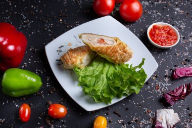 kırmızı soslu tavuk rulo, kırmızı domates, ekmek, kırmızı yeşil biber ve brokoli ile siyah arka plan üzerinde, üst görünümü