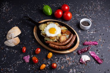 patates ve kızarmış yumurta ile pişmiş sosis, kırmızı domates, ekmek, kırmızı yeşil biber ve brokoli, lama, üst görünümü ile siyah arka plan üzerinde, restoran servis