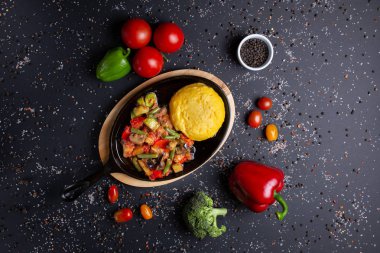 güveç tava ile polenta, siyah arka plan, domates, kırmızı yeşil biber ve brokoli ile, üst görünümü