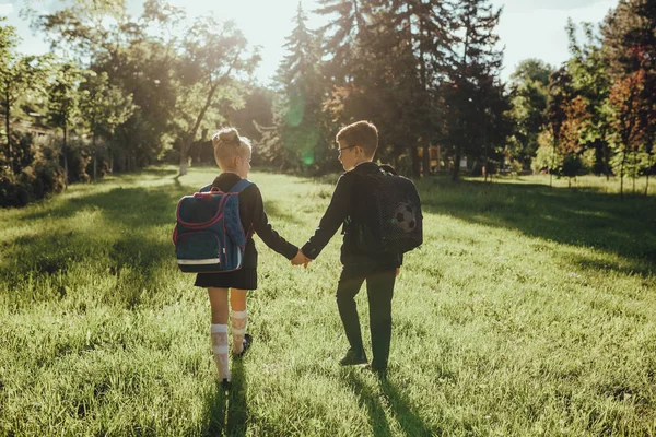 Dvě malé děti, vracející se do školy, venkovní, při západu slunce, — Stock fotografie