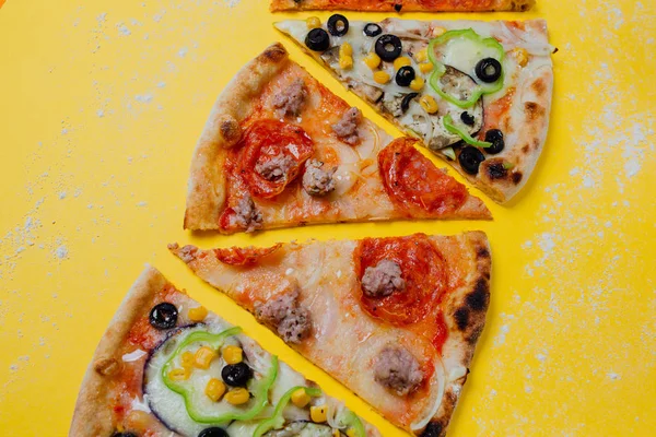 four different pizza, tasty sliced pizza,  sliced peppers, yellow background, Top view. Banner, close-up, copy-space
