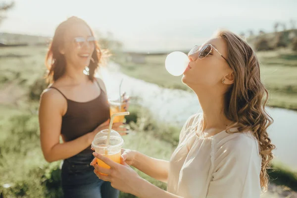 Dvě Mladé Dívky Sfoukala Bublinu Žvýkačky Pijí Pomerančový Džus Plastovém — Stock fotografie