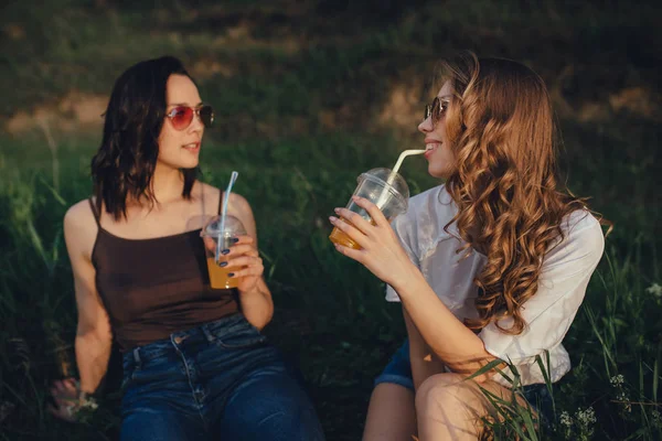 Dos Amigas Felices Son Alegres Sentarse Hierba Beber Jugo Naranja — Foto de Stock