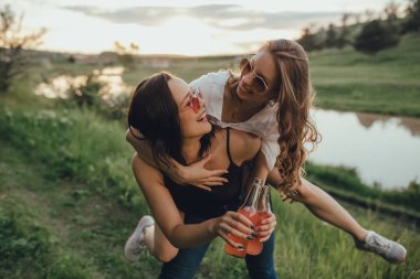 eğlenceli kızlar iki şişe tutuyor. güneş gözlüğü, eğlenceli yaşıyor, gün batımı, pozitif yüz ifadesi, açık, sevinç kavramı