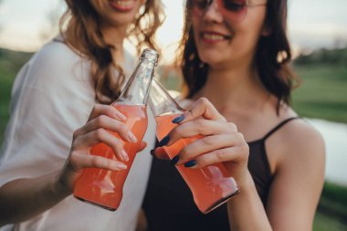 yaşam tarzı insan kavramı kadar yakın. iki mutlu kız eğlenmek, el pembe şişe tutmak, yaz, gün batımında eğlenceli, açık