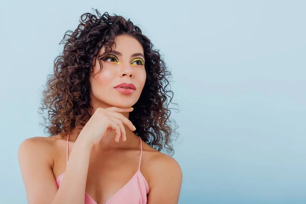 close up. young lady with curly hair dressed in a pink shirt, isolated on blue background, copy space
