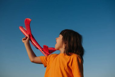 küçük kız elinde kırmızı bir uçak tutar, açık havada, gökyüzü arka plan, kopya alanı