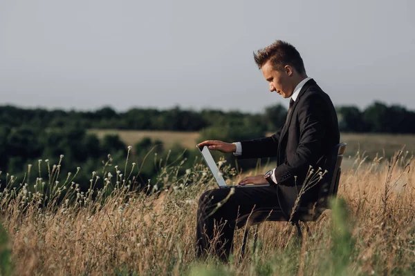 Mladý podnikatel s laptopem v terénu, venkovní, profilový pohled — Stock fotografie