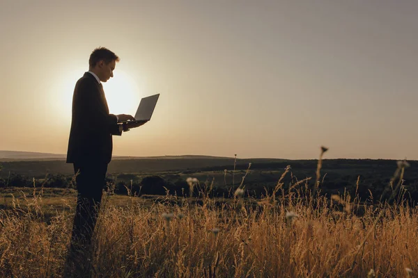 young man using laptop, Internet and social network concept, at sunset, copy space, profile view, outdoor