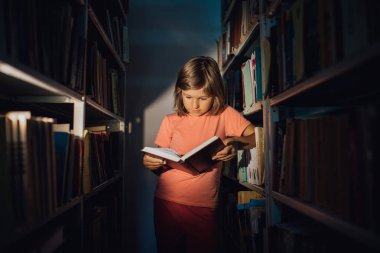 Küçük kız kütüphanede öğreniyor. elinde bir kitap tutar, kapalı, 1