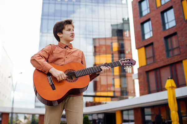 Preteen joue de la guitare dans le parc, vue du bas, habillé d'une chemise , — Photo