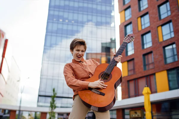 Enfant enthousiaste joue de la guitare dans le parc, vêtu d'une chemise , — Photo