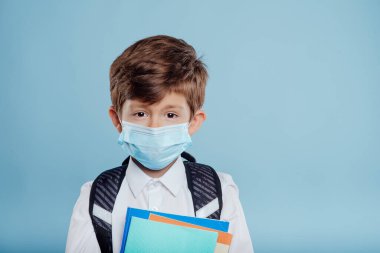 Okula geri dön, tıbbi maskeli ve sırt çantalı küçük çocuk.,