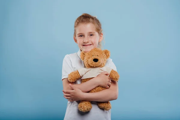 Boldog kislány medve játék elszigetelt kék háttér, — Stock Fotó