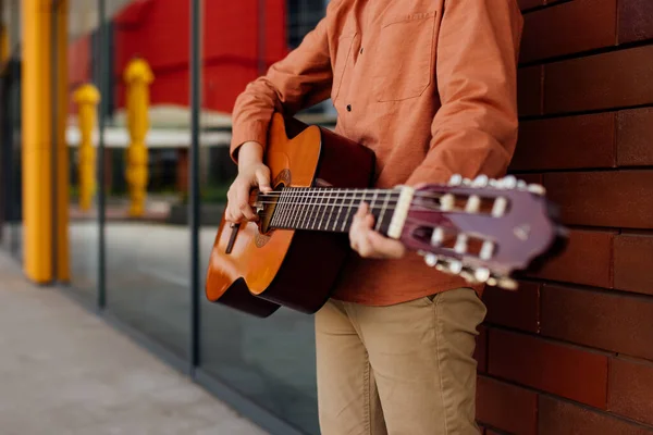 Gros plan, garçon avec guitare, appuyé contre le mur de briques, vêtu d'une chemise — Photo