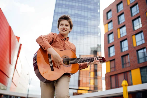 Beau préadolescent joue de la guitare dans le parc, vue du bas , — Photo