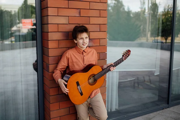 Garçon avec guitare, appuyé contre le mur de briques, vêtu d'une chemise , — Photo