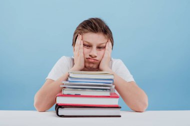 Stüdyoda oturup ders çalışırken sıkılmış ve bitkin düşmüş bir çocuk.