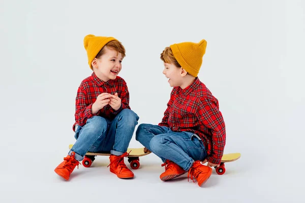 Twee blije jongetjes zitten op het skateboard, — Stockfoto