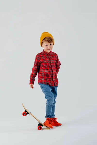 Маленький мальчик с ногой на скейтборде, одетый в красную рубашку — стоковое фото