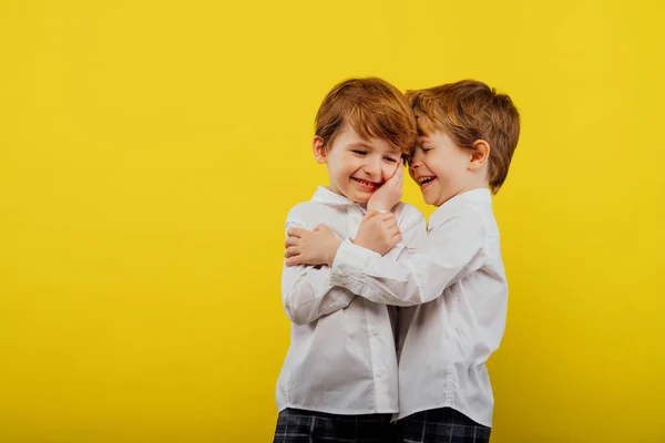 Два маленьких хлопчика обіймаються, граються, одягнені в білу сорочку — стокове фото