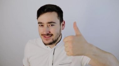 Başparmağı havada, kameraya bakan yakışıklı bir genç.